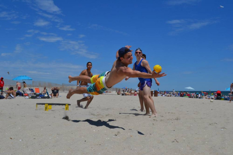 Spikeball Actionspiel am Strand mit Hechtsprung